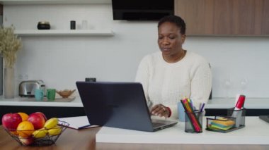 Yoğun Afrikalı kadın laptopla evde fazladan mesai yapıyor.