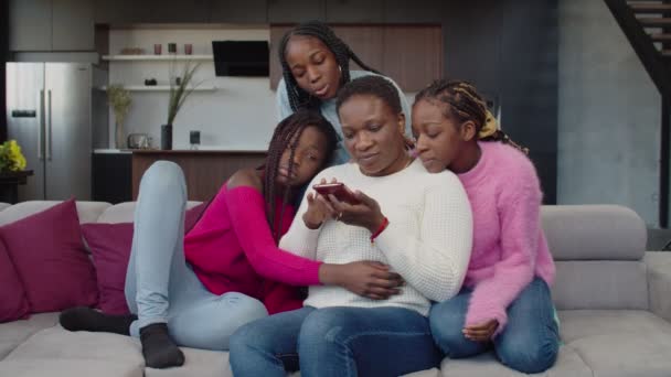 Joyful black family networking e compartilhamento de celular no sofá — Vídeo de Stock