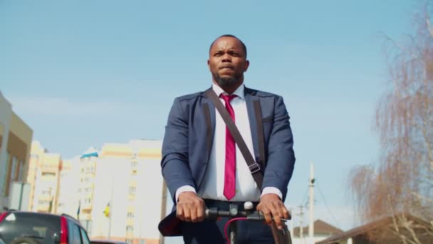 Empresário africano agradável dirigindo scooter elétrico ao ar livre — Vídeo de Stock