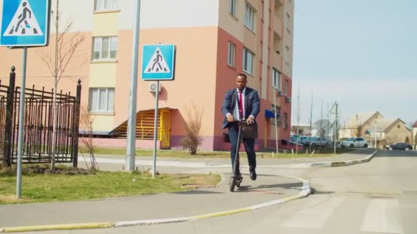 Afikanischer Geschäftsmann im Anzug fährt auf Elektro-Tretroller auf der Straße — Stockvideo