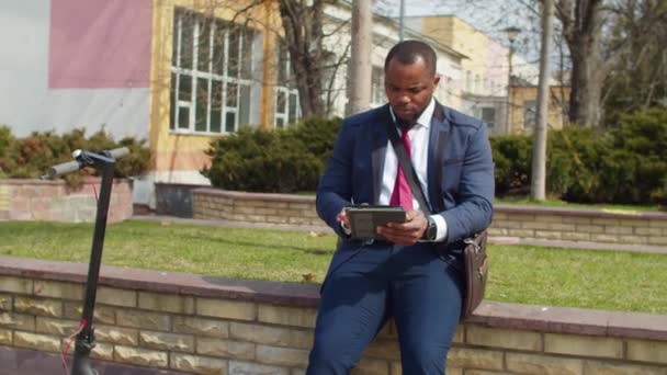 Black businessman networking on tablet pc in public park — Stock Video