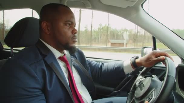 Vista lateral del hombre de negocios africano que conduce el coche en la carretera — Vídeos de Stock