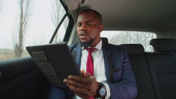 Empresario negro ocupado hablando en video chat en vehículo — Vídeos de Stock