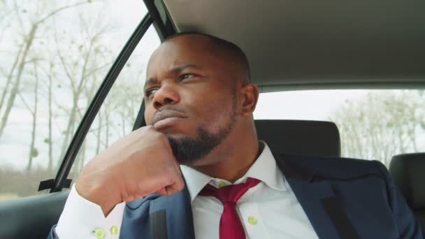 Pensiv trött svart man chef i bilen tittar ut genom fönstret — Stockvideo