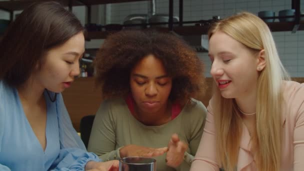 Joyful multiethnic girlfriends whispering gossip at cafe — Stock Video