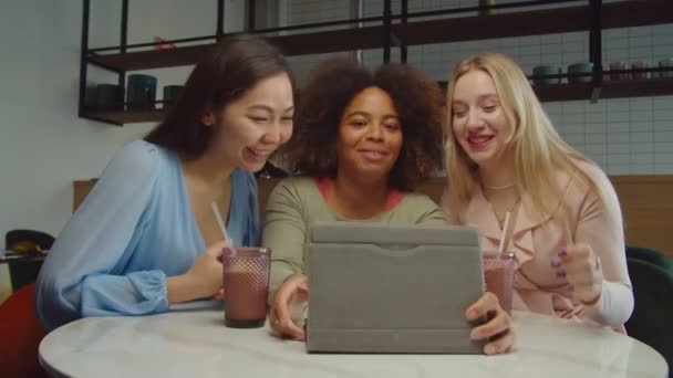 Femmes multiraciales naviguant contenu en ligne sur tablette PC au café — Video