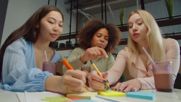 Equipo empresarial femenino reuniendo ideas sobre notas adhesivas en la cafetería — Vídeos de Stock