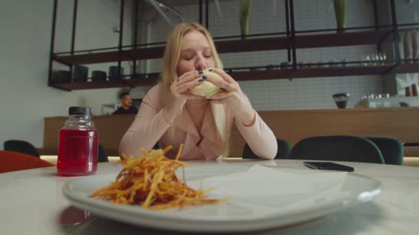 Behoorlijk charmant vrouwtje genietend van lekkere gegrilde burger in café — Stockvideo