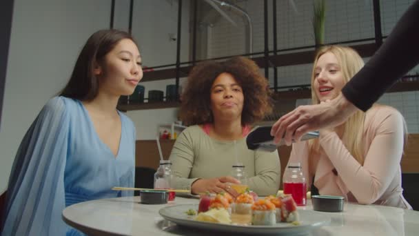 Diverse female friends deciding who paying bill at cafe — Stock Video