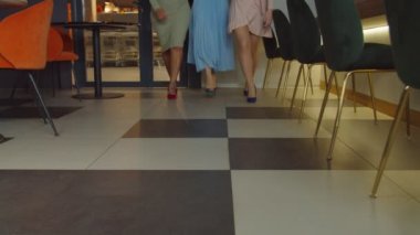 Yüksek topuklu ayakkabılı ince kadın bacakları kafeye giriyor.