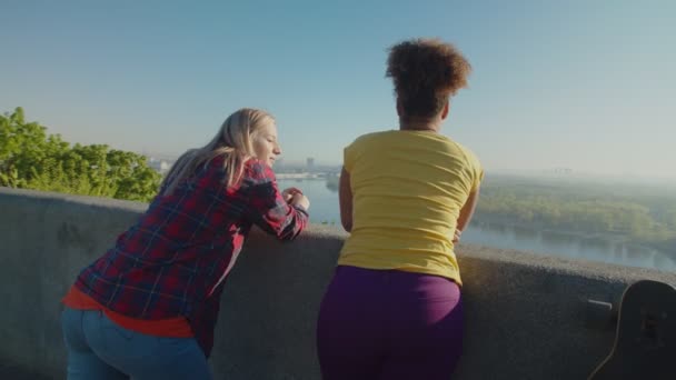 Rückansicht ziemlich unterschiedlicher Frauen, die das Stadtbild bei Sonnenaufgang genießen — Stockvideo