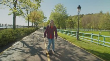 Neşeli, sevimli kaykaycı kadın kaykay yaparken özgürlüğün tadını çıkarıyor.