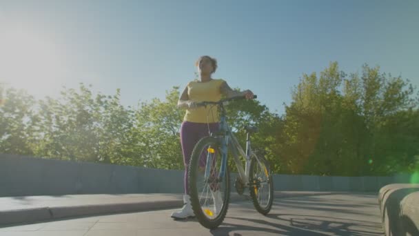 Vidám, aktív fekete nő kerékpárral sétál a városban hajnalban — Stock videók