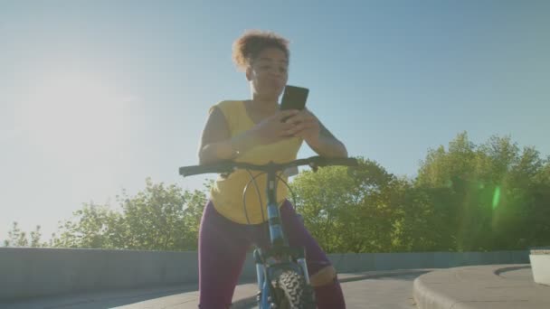 Linda mulher negra em rede de bicicletas no celular ao amanhecer — Vídeo de Stock