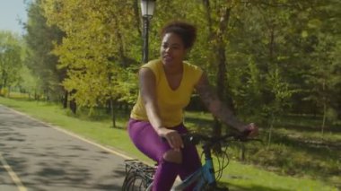 Parkta bisiklet süren neşeli, Afrikalı bir bisikletçi.