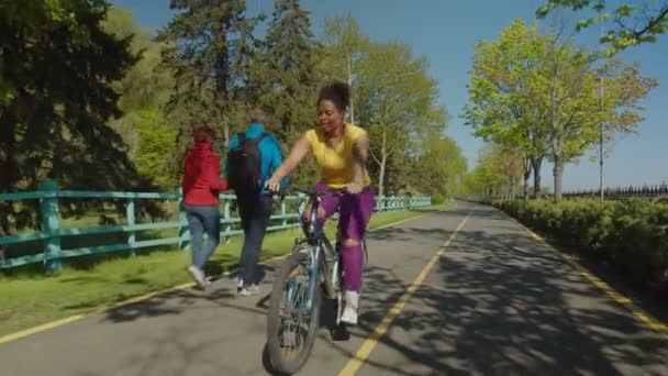 Positivo bella donna africana americana in bicicletta attraverso il parco pubblico — Video Stock