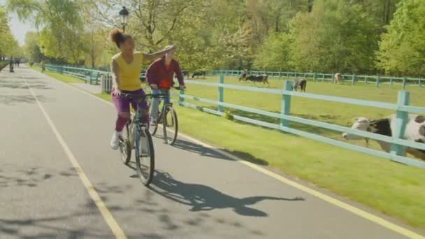 Беззаботные многорасовые подруги, гоняющиеся на велосипедах на улице — стоковое видео