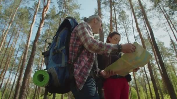 Wandelaars paar met rugzakken navigeren met kaart op tocht in de natuur — Stockvideo
