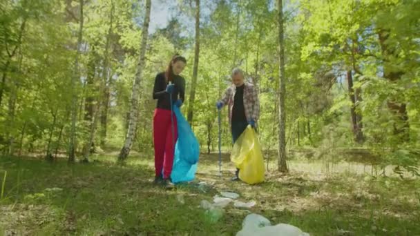 숲 속에서 청소를 하다가 쓰레기를 모으는 환경에 깨어 있는 자원 봉사자들 — 비디오