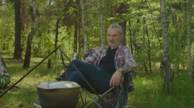 Relaxed mature traveler man enjoying leisure at campsite