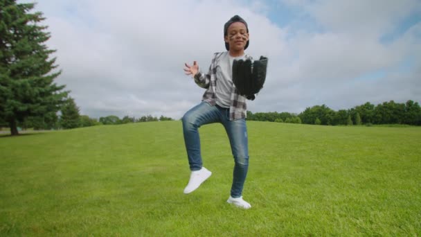 Vreugdevolle school leeftijd Afrikaanse jongen met honkbal handschoen en bal dansen op het veld — Stockvideo