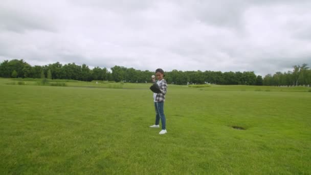 Щасливий шкільний вік чорний хлопчик в бейсбольній рукавичці на зеленому полі — стокове відео