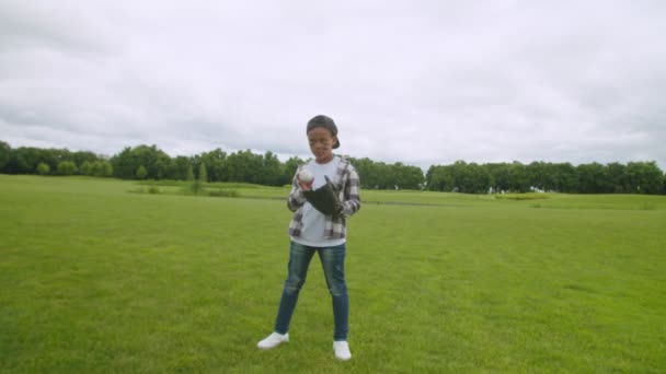 Портрет милого маленького африканського хлопчика, який кидає бейсбол на відкритому повітрі — стокове відео