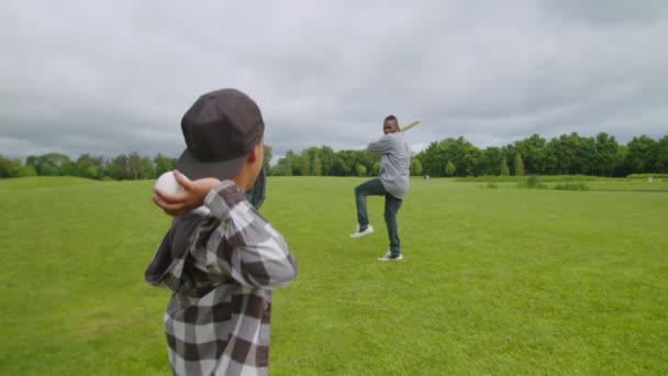 Primer plano del hijo africano lanzando béisbol al bateo padre al aire libre — Vídeos de Stock