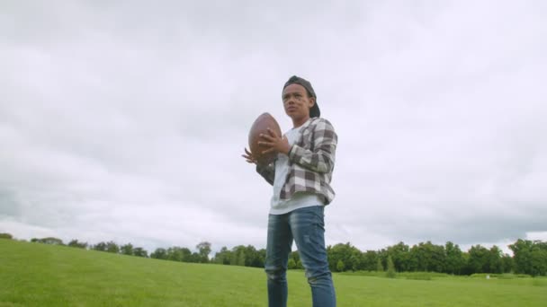 Positivo niño lanzando pelota de fútbol americano a papá al aire libre — Vídeo de stock