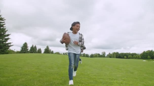 Opgewonden kleine zwarte jongen met amerikaanse voetbal running naar touchdown scoren — Stockvideo