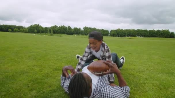 Радісний африканський тато під час американського футбольного матчу бився з милим сином. — стокове відео