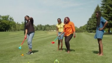 Kaygısız Afrikalı aile park çimlerinde kriket oynarken eğleniyor.