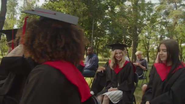 Diverse multi-etnische studenten en ouders verzamelen zich voor afstudeerceremonie op de campus — Stockvideo