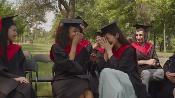 Διαφορετικές πολυφυλετικές γυναίκες απόφοιτοι σε ακαδημαϊκά φορέματα αγκαλιάζει την ημέρα αποφοίτησης — Αρχείο Βίντεο