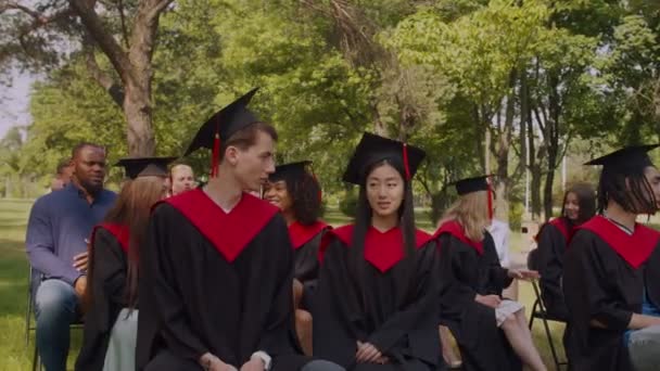 Retrato de diversos graduados multirraciales en vestidos académicos en el día de la graduación — Vídeo de stock