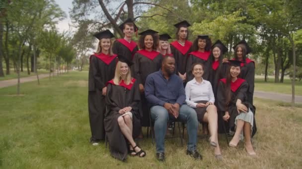 Retrato conjunto del personal académico y los graduados multirraciales al aire libre — Vídeo de stock