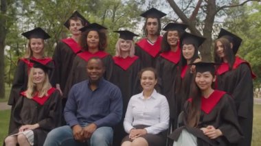 Mutlu çok ırklı mezunlar ve akademik personel birlikte poz veriyor.