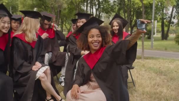 Porträt unbeschwerter Studenten im Abschlussdress, die am Abschlusstag ein Selfie machen — Stockvideo
