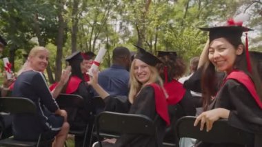 Çeşitli etnik çeşitlilikteki başarılı akademik mezunlar diplomalarını gösteriyor.