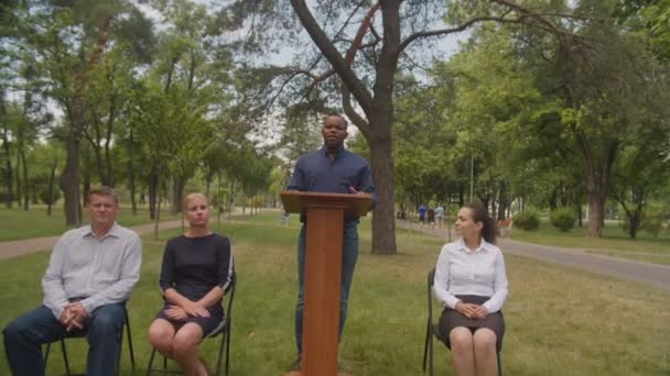 Professor negro positivo dando conversa com graduados multirraciais no dia da formatura — Vídeo de Stock