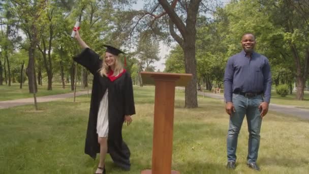 Восхитительная женщина-выпускница празднует получение университетского диплома в день выпуска — стоковое видео