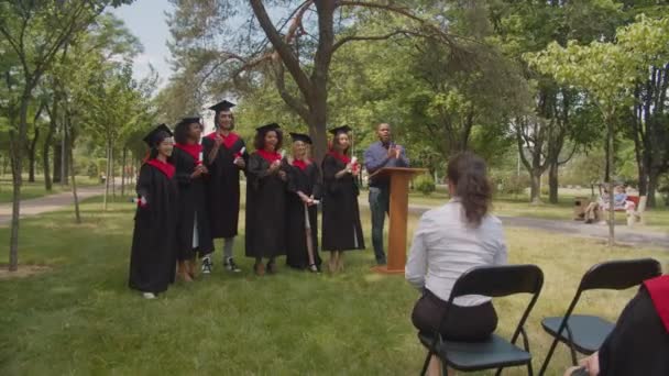 Alegre diversos graduados multiétnicos celebrando el título universitario en el día de la graduación — Vídeo de stock