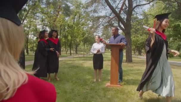 Graduados multirraciales felices recibiendo diplomas de decano en el día de la graduación — Vídeo de stock