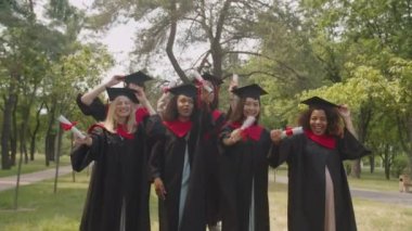 Mezuniyet gününü kutlayan, havaya havan topu fırlatan neşeli, çeşitli çok ırklı mezunlar.