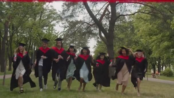 Graduados multiétnicos diversos sin preocupaciones con diplomas que corren para cruzar la línea de meta al aire libre — Vídeo de stock