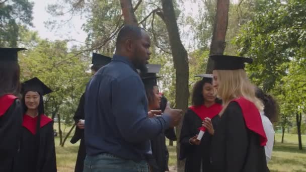 Glade multietniske kandidater og akademisk personale taler efter eksamen ceremoni – Stock-video