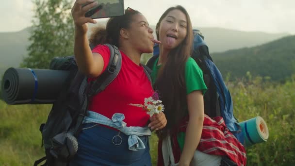 Zorgeloos vrij multiraciale vrouwen wandelaars maken selfie op de telefoon in de bergen bij zonsondergang — Stockvideo