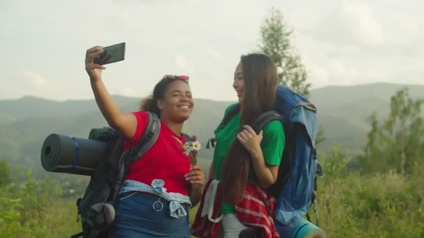 Despreocupado bastante multiétnicos viajeros femeninos tomando selfie tiro en la montaña al atardecer — Vídeos de Stock
