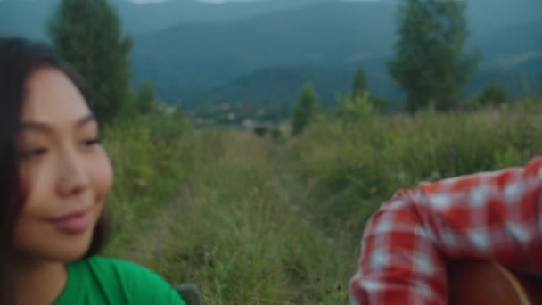 Χαλαρωμένοι πολυφυλετικοί ταξιδιώτες που απολαμβάνουν τον ελεύθερο χρόνο, παίζοντας μουσική στο λόφο του βουνού — Αρχείο Βίντεο