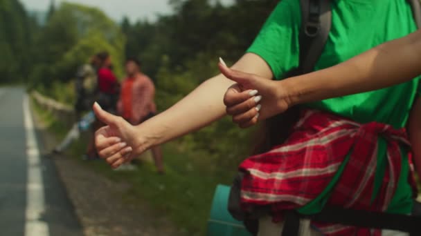 山岳道路でヒッチハイク中に親指を立てる多人種の女性の手のクローズアップ — ストック動画